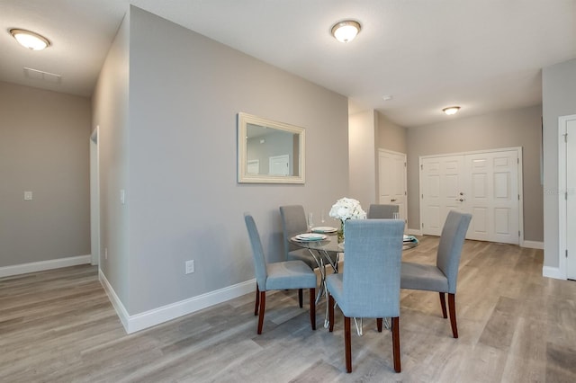 dining space with light wood finished floors, visible vents, and baseboards