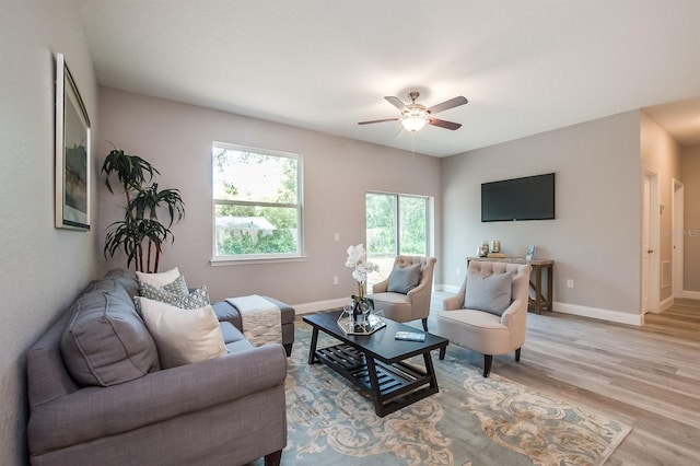 living room featuring light wood-style flooring, baseboards, and a ceiling fan