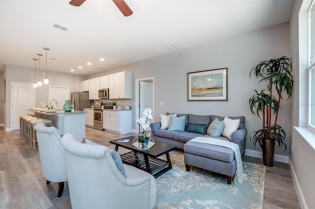 living area with ceiling fan, light wood-style flooring, recessed lighting, visible vents, and baseboards