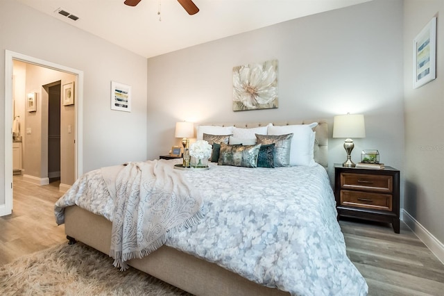 bedroom featuring a ceiling fan, visible vents, baseboards, and wood finished floors