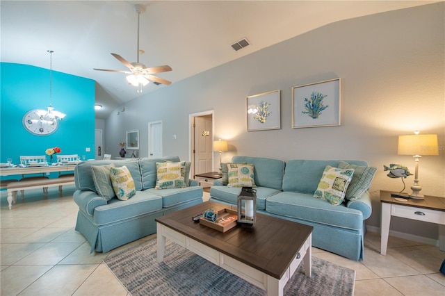 tiled living room featuring ceiling fan with notable chandelier and high vaulted ceiling