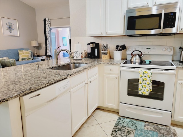 kitchen with white cabinets, light stone counters, white appliances, and sink