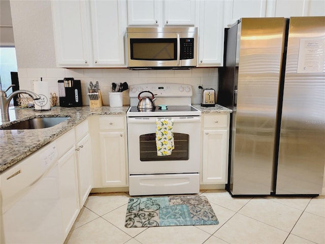 kitchen with light stone countertops, sink, white cabinets, and stainless steel appliances