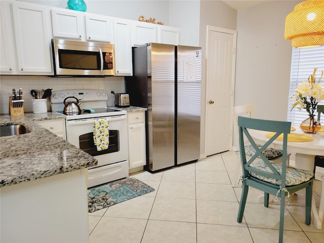 kitchen featuring white cabinetry, light stone counters, backsplash, light tile patterned floors, and appliances with stainless steel finishes