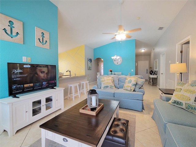 living room with ceiling fan with notable chandelier, light tile patterned floors, and lofted ceiling