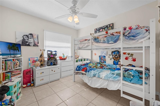 bedroom with ceiling fan, light tile patterned flooring, and a textured ceiling