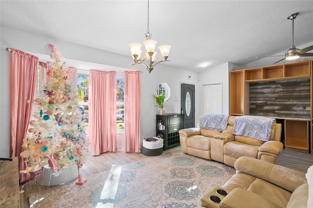 living room featuring ceiling fan with notable chandelier, lofted ceiling, a textured ceiling, and light hardwood / wood-style flooring