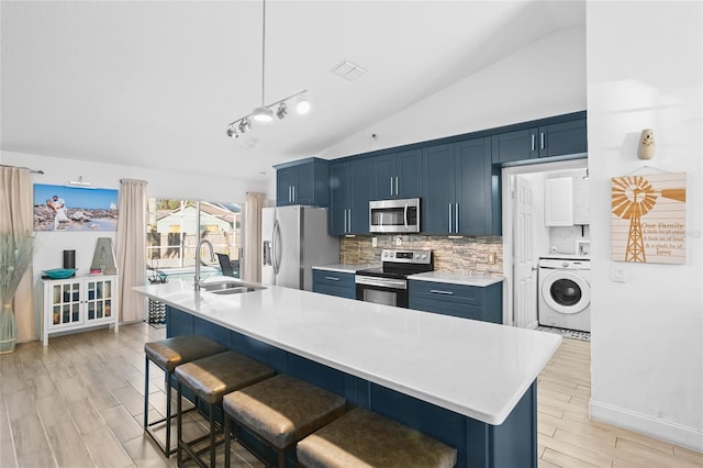 kitchen with blue cabinetry, sink, washer / clothes dryer, a breakfast bar, and appliances with stainless steel finishes