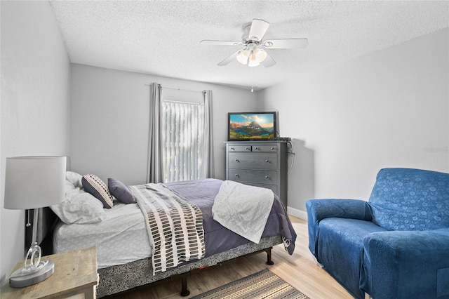 bedroom with ceiling fan, a textured ceiling, and hardwood / wood-style flooring