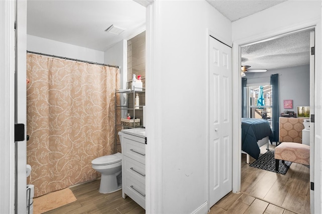 bathroom with ceiling fan, toilet, wood-type flooring, and a textured ceiling