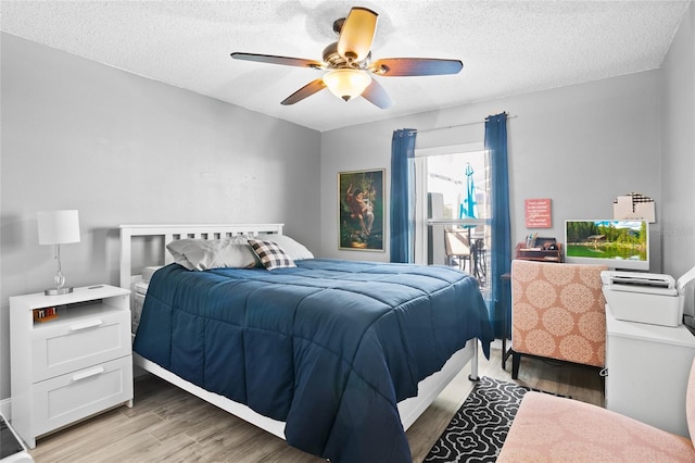 bedroom featuring ceiling fan, light hardwood / wood-style floors, and a textured ceiling