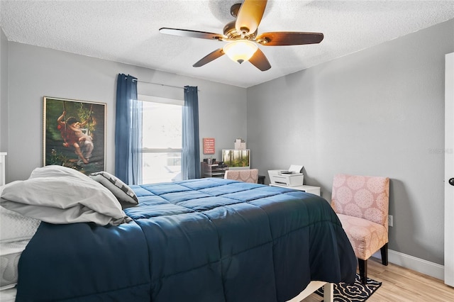 bedroom with ceiling fan, light hardwood / wood-style floors, and a textured ceiling