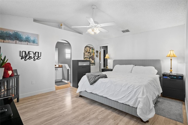 bedroom with a textured ceiling, light hardwood / wood-style flooring, ceiling fan, and lofted ceiling