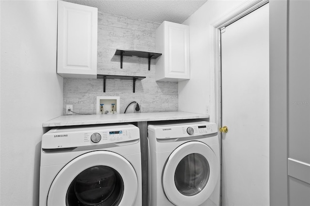 washroom with cabinets, a textured ceiling, and washer and clothes dryer