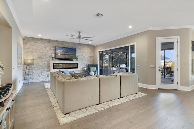 living area featuring a glass covered fireplace, a healthy amount of sunlight, visible vents, and wood finished floors