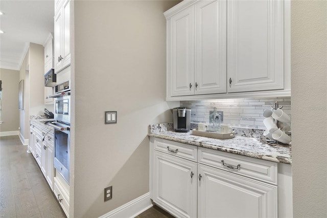 kitchen with oven, white cabinets, backsplash, and baseboards