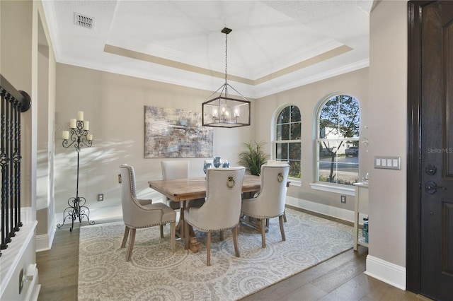 dining space featuring crown molding, a raised ceiling, visible vents, dark wood-type flooring, and baseboards