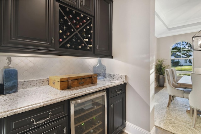 bar with crown molding, tasteful backsplash, a bar, beverage cooler, and baseboards