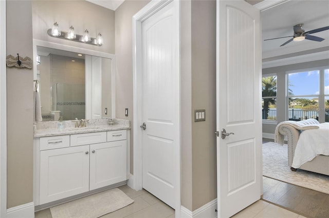 bathroom with a stall shower, ensuite bath, baseboards, and vanity