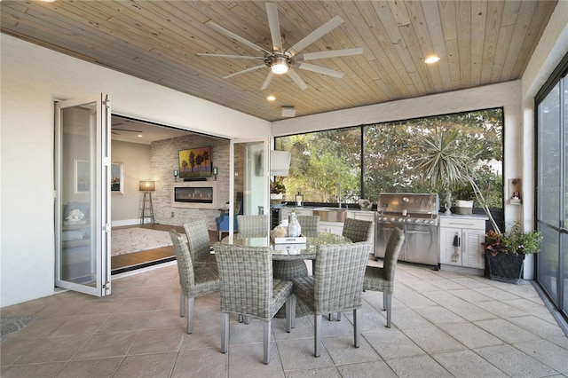 sunroom with ceiling fan, a glass covered fireplace, and wood ceiling