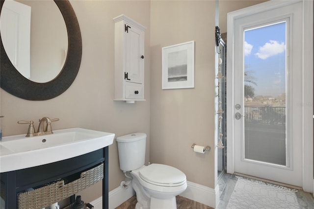 full bathroom with toilet, baseboards, a shower, and a sink