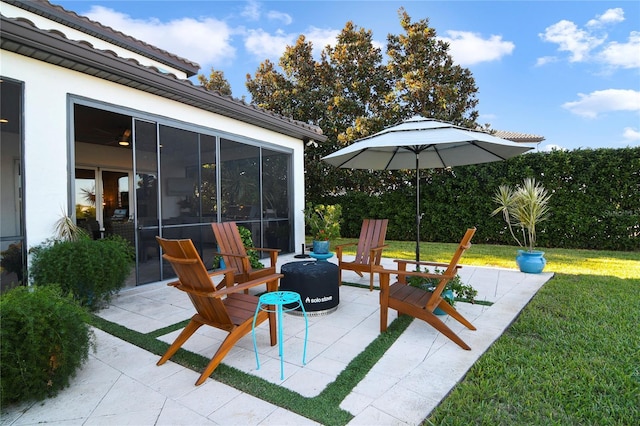 view of patio / terrace with a sunroom and a fire pit