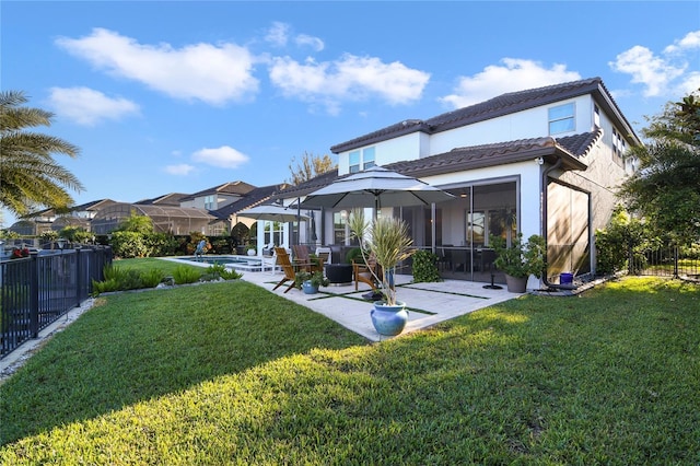 rear view of property featuring a lawn, a patio area, fence, and an outdoor pool