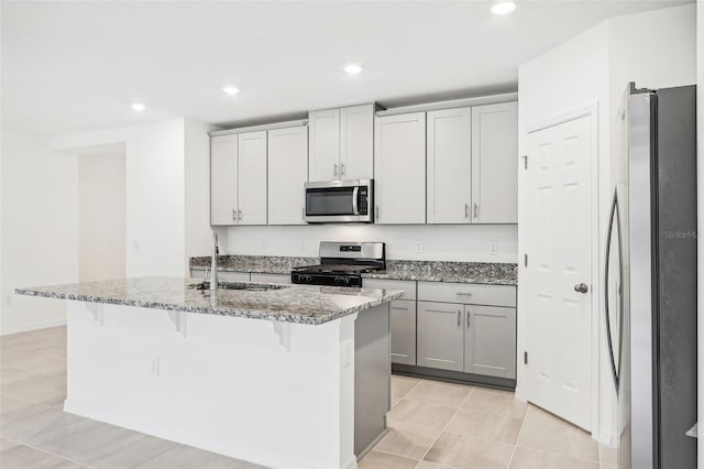 kitchen featuring a kitchen bar, an island with sink, stainless steel appliances, and sink