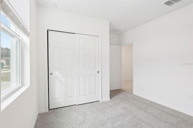 unfurnished bedroom with light carpet and a closet