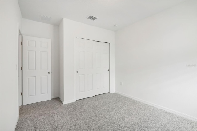 unfurnished bedroom with light colored carpet and a closet