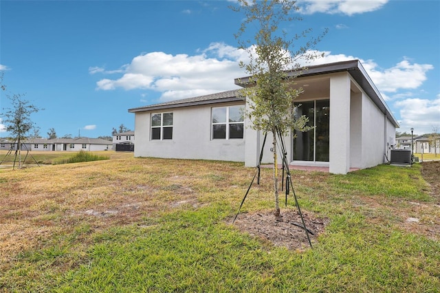 rear view of property with a yard and central air condition unit