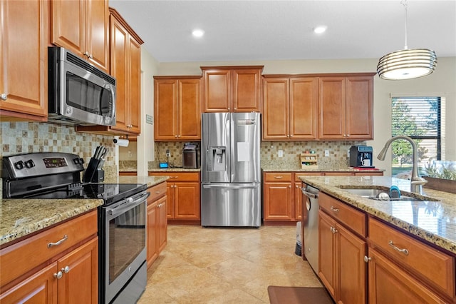 kitchen with light stone countertops, sink, stainless steel appliances, backsplash, and decorative light fixtures