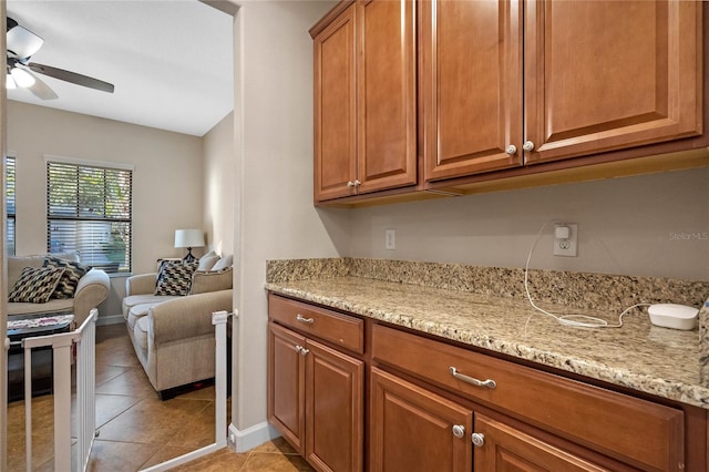 kitchen featuring ceiling fan, light tile patterned flooring, and light stone countertops