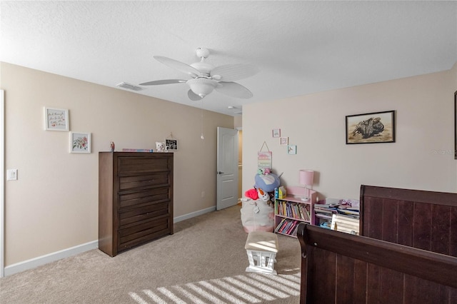 bedroom with ceiling fan, light colored carpet, and a textured ceiling