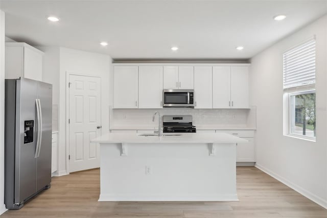 kitchen featuring a center island with sink, light hardwood / wood-style floors, white cabinets, and stainless steel appliances