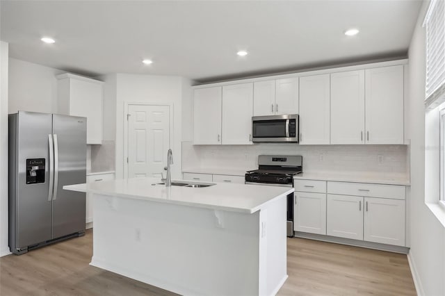 kitchen with sink, light hardwood / wood-style flooring, a center island with sink, white cabinets, and appliances with stainless steel finishes