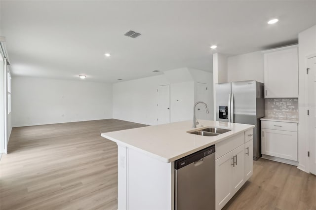 kitchen with white cabinets, sink, stainless steel appliances, and an island with sink