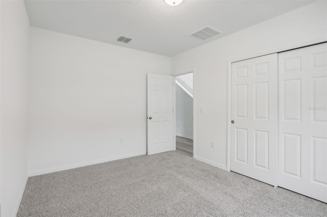 unfurnished bedroom with a closet and light colored carpet