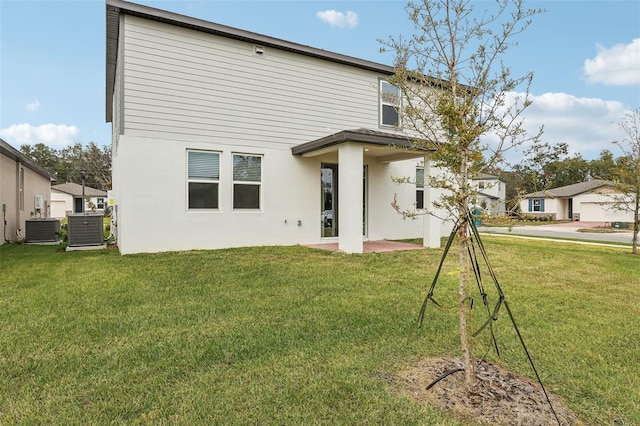 rear view of house with central AC unit and a yard