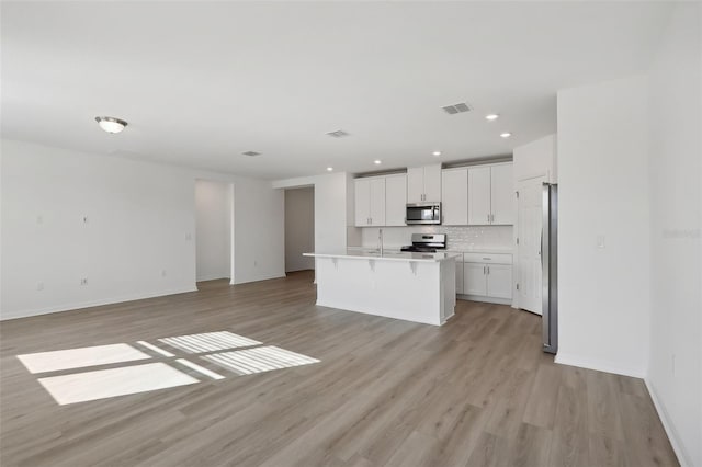 kitchen with white cabinetry, sink, a center island with sink, appliances with stainless steel finishes, and light wood-type flooring