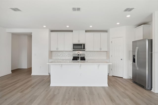 kitchen featuring white cabinetry, a kitchen island with sink, light hardwood / wood-style floors, and appliances with stainless steel finishes