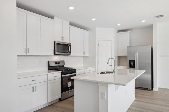 kitchen with white cabinets, light wood-type flooring, a kitchen island with sink, and appliances with stainless steel finishes