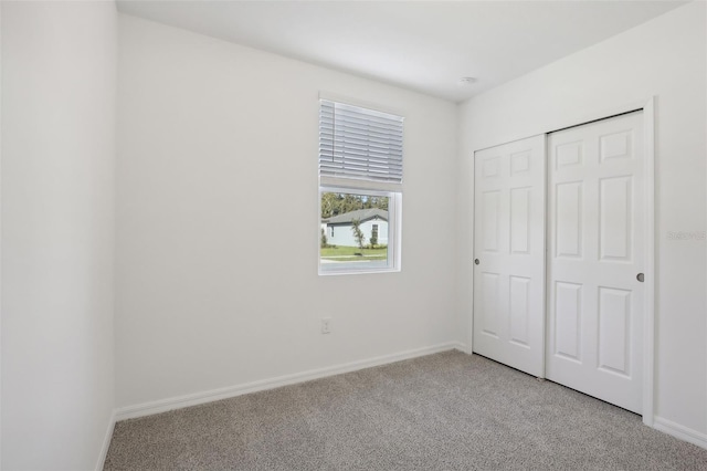 unfurnished bedroom featuring light carpet and a closet