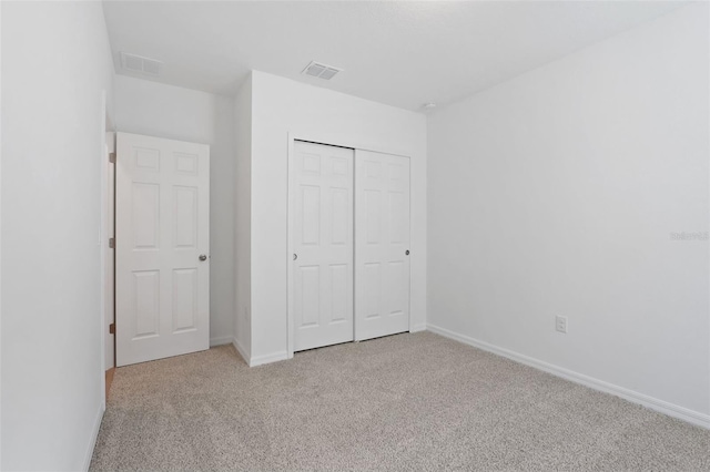 unfurnished bedroom with light carpet and a closet