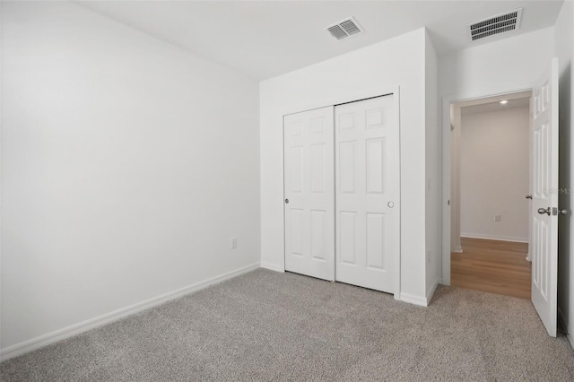 unfurnished bedroom with light colored carpet and a closet