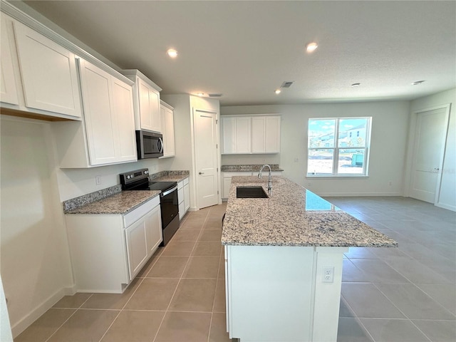 kitchen with sink, black electric range, an island with sink, white cabinetry, and light tile patterned flooring