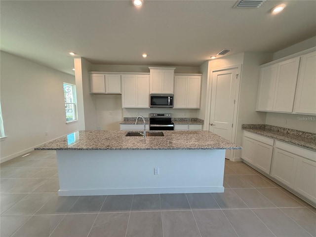 kitchen with a sink, stainless steel appliances, light stone counters, and white cabinets