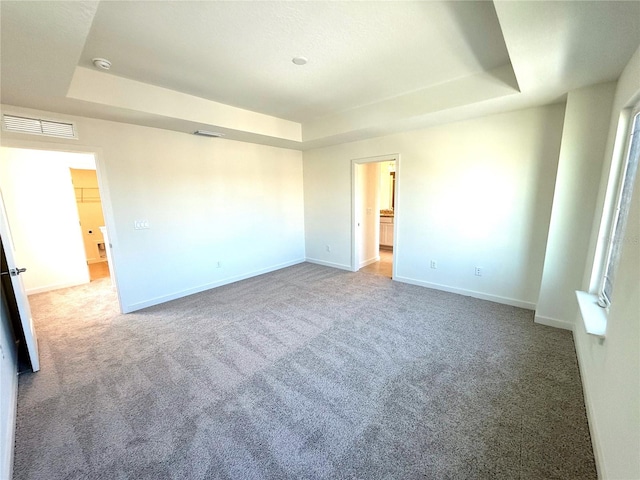 unfurnished bedroom featuring a tray ceiling, carpet flooring, and baseboards