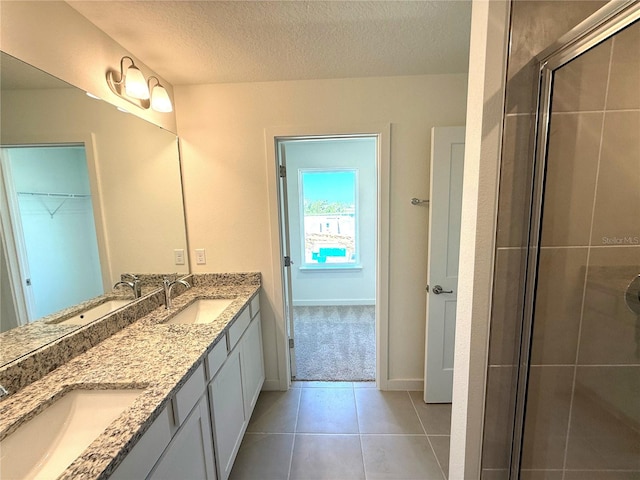 bathroom with vanity, a shower with door, tile patterned flooring, and a textured ceiling