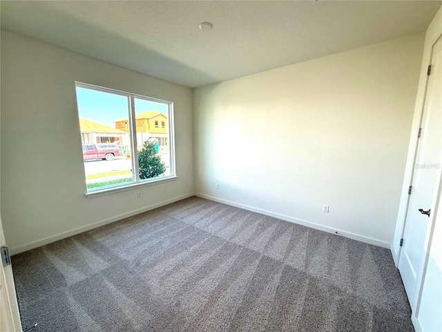 carpeted empty room featuring baseboards